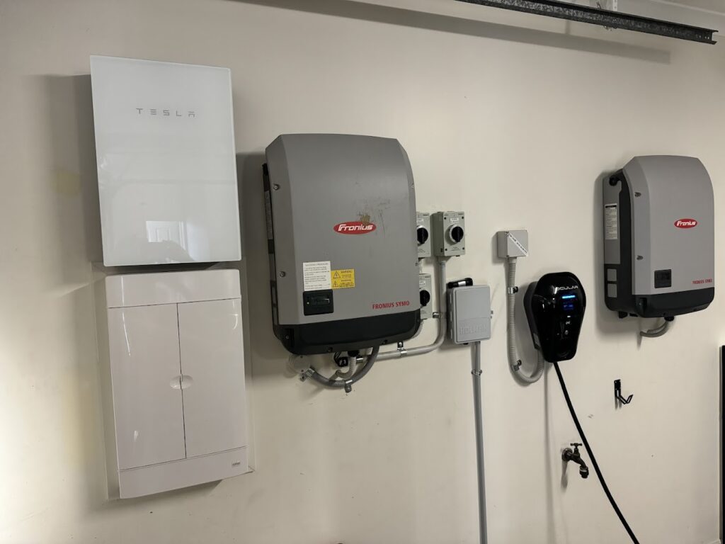 Electric vehicle charger being professionally installed on the exterior wall of a home, showcasing a sleek black charging unit connected to the electrical system for convenient at-home EV charging.